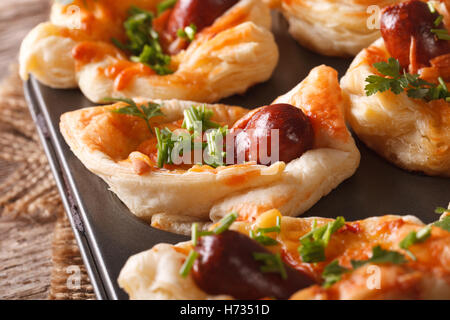Des petits pains à saucisse feuilletée avec, le fromage et l'oignon dans le plat de cuisson macro horizontale. Banque D'Images