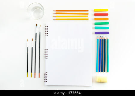 La maquette de l'art de croquis à l'aquarelle peintures, pastels, verre d'eau et un pinceaux. Vue d'en haut. Outils de travail artistique Banque D'Images