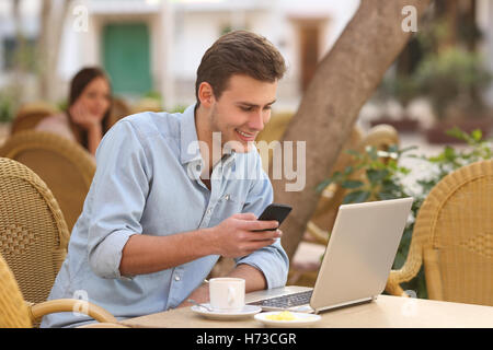L'homme indépendant travaillant avec un ordinateur portable et un téléphone dans un restaurant Banque D'Images