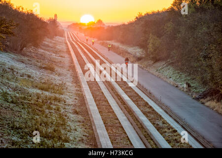 Plus de Cambridgeshire, Royaume-Uni, 2 novembre 2016. Cyclistes roulent vers Cambridge comme le soleil se lève sur les pistes d'un clair et net, frosty matin d'automne. L'air clair et première gelée d'automne dans l'Est de l'UK jeter une lumière dorée sur le trajet du matin. Julian crédit Eales/Alamy Live News Banque D'Images