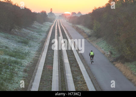 Plus de Cambridgeshire, Royaume-Uni, 2 novembre 2016. Cyclistes roulent vers Cambridge comme le soleil se lève sur les pistes d'un clair et net, frosty matin d'automne. L'air clair et première gelée d'automne dans l'Est de l'UK jeter une lumière dorée sur le trajet du matin. Julian crédit Eales/Alamy Live News Banque D'Images