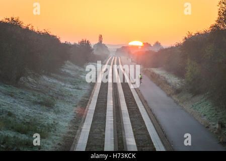 Plus de Cambridgeshire, Royaume-Uni, 2 novembre 2016. Cyclistes roulent vers Cambridge comme le soleil se lève sur les pistes d'un clair et net, frosty matin d'automne. L'air clair et première gelée d'automne dans l'Est de l'UK jeter une lumière dorée sur le trajet du matin. Julian crédit Eales/Alamy Live News Banque D'Images