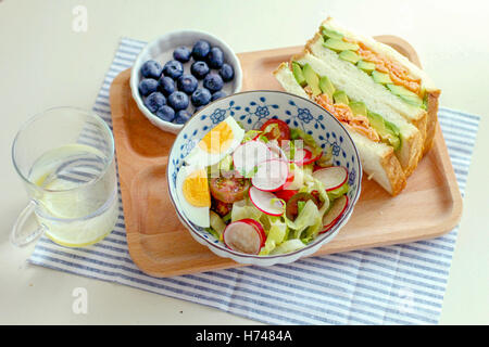 Poulet sandwich sain d'avocat, salade aux œufs et de bleuet sur un plateau avec un verre d'eau Banque D'Images