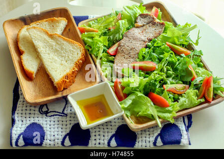 Les steaks grillés et salade de légumes et le pain coupé en tranches. Banque D'Images