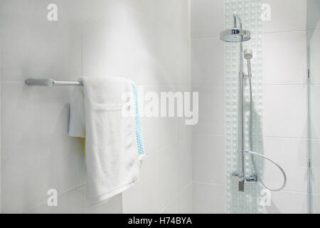 Intérieur de salle de bains avec douche moderne et tête serviette blanche à rail dans une salle de bains privative. Banque D'Images