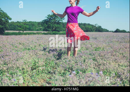 Une jeune femme est en train de tourner autour dans un champ de fleurs violettes sur une journée ensoleillée Banque D'Images