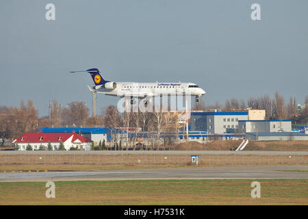 Borispol, l'Ukraine - 13 novembre 2010 : Lufthansa Canadair CL-600 de jets régionaux CRJ-701ER C'est l'atterrissage à l'aéroport avec quelques buil Banque D'Images