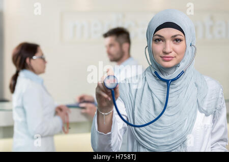 Vue de face d'une femme médecin arabe montrant stéthoscope. Banque D'Images