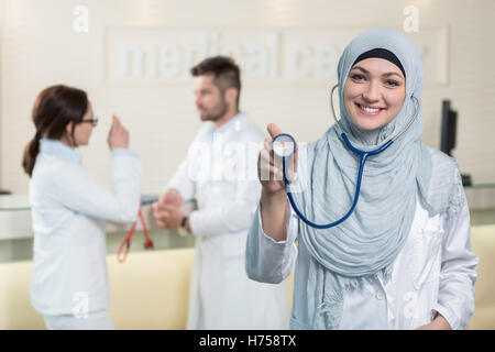 Vue de face d'une femme médecin arabe montrant stéthoscope. Banque D'Images