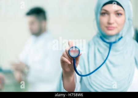 Vue de face d'une femme médecin arabe montrant stéthoscope. Banque D'Images