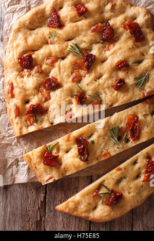 Des tranches de pain focaccia italienne aux tomates séchées et romarin fermer vers le haut sur la table. Vue verticale d'en haut Banque D'Images