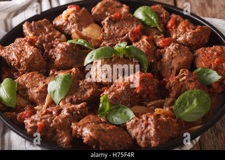 Stifado grec d'un boeuf avec la sauce et le basilic close up dans un plat. Banque D'Images