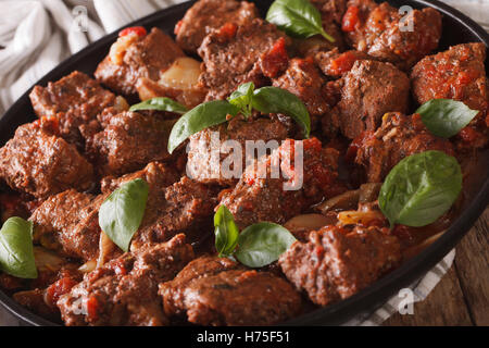Boeuf sauce stifado grec avec basilic et macro sur la plaque horizontale. Banque D'Images