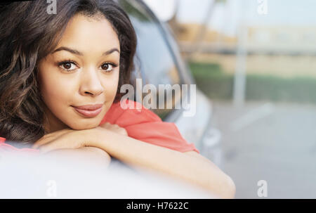 Pretty young woman leaning out of car window Banque D'Images