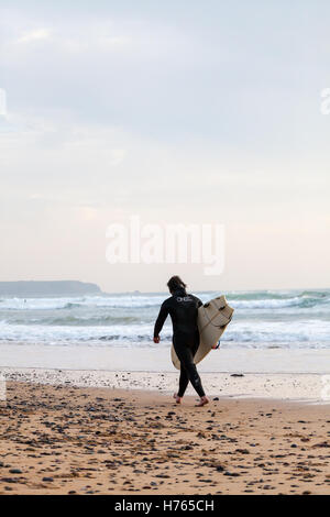 Un Surfer carrying surfboard at Freshwater West Beach, Pembrokeshire en automne Banque D'Images