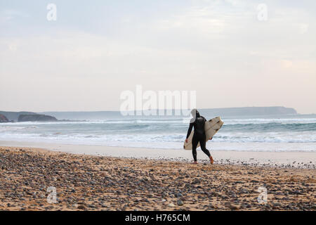 Un Surfer carrying surfboard at Freshwater West Beach, Pembrokeshire en automne Banque D'Images