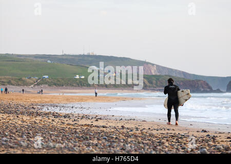 Un Surfer carrying surfboard at Freshwater West Beach, Pembrokeshire en automne Banque D'Images