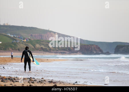 Un Surfer carrying surfboard at Freshwater West Beach, Pembrokeshire en automne Banque D'Images