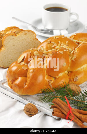 Ensemble et les tranches de pain tressé sucré aux amandes et raisins secs sur planche à découper en bois et serviette blanche Banque D'Images