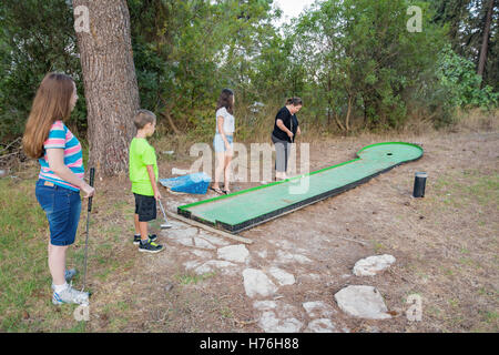 Mère et trois enfants jouant au golf miniature en plein air dans une forêt Galilée dans le nord d'Israël Banque D'Images