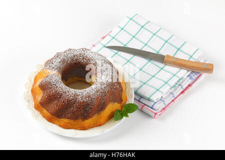 En gâteau bundt, couteau de cuisine et torchons à carreaux sur fond blanc Banque D'Images