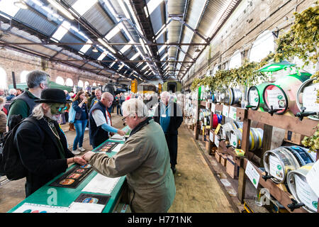 CAMRA beer festival dans le vieux hangar à locomotives Tunbridge Wells, Royaume-Uni. La sélection de personnes de diverses bières, fûts, barils de bière derrière un long comptoir. Banque D'Images