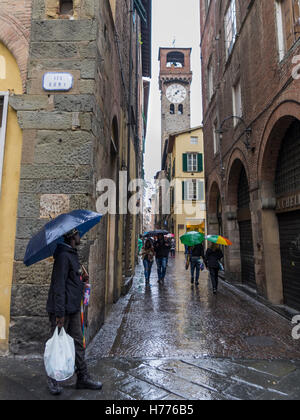 Les gens avec des parasols dans une ruelle de la vieille ville de Lucca, Toscane, Italie, un jour de pluie. Banque D'Images