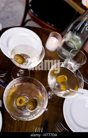 La vodka, gin ou trois martinis dans classic lunettes avec les olives. Photographié dans un format vertical de surcharge dans un café. Pas de gens, pas de nourriture. Attente Banque D'Images