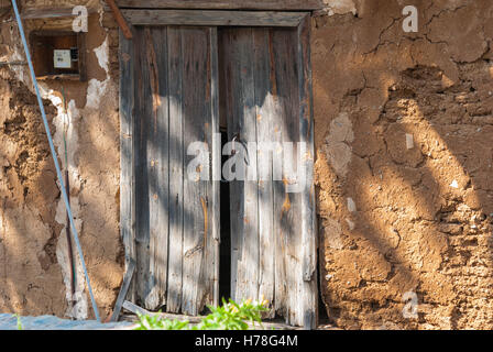 Vieille porte en bois miteux bleu avec charnières rouillées à l'entrée de la vieille maison en pierre chypriote. (Phikardou Fikardou) village. Chypre. Banque D'Images