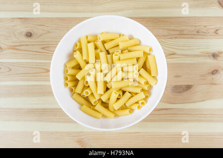 Les pâtes non cuites brutes tortiglioni vu de dessus en bol blanc sur la table en bois Banque D'Images