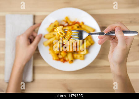 Cuire les pâtes tortiglioni sur fourche close up. Au-dessus de la fourchette de main de femme tenant la plaque de pâtes au four. Banque D'Images