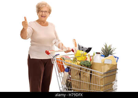 Cheerful mature dame avec un panier plein de provisions de donner un pouce vers le haut isolé sur fond blanc Banque D'Images