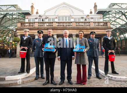 Lance Corporal Richard Jones (troisième à partir de la gauche), le secrétaire à la défense, Michael Fallon (centre) et la chanteuse Laura Wright à l'occasion du lancement de la Journée du coquelicot Londres, qui voit 2 000 membres du personnel de service pour la collecte de la Royal British Legion's pavot annuel appel à Covent Garden, Londres. Banque D'Images