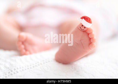 Un gros plan de tout petit bébé pieds avec Santa Claus hat - Merry Christmas Gift Banque D'Images