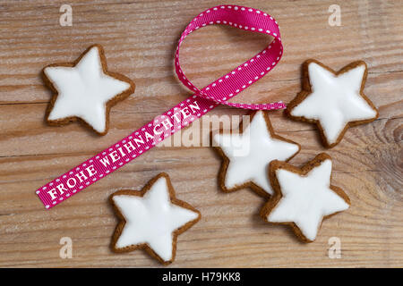 Étoiles à la cannelle sur bois avec Frohe Weihnachten (en allemand) joyeux noël ruban cadeau. Banque D'Images