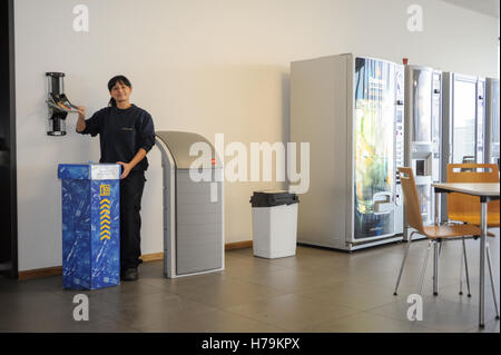 Genève, Suisse - 13 janvier 2014 : jeune fille qui est le recyclage d'une bouteille de PET dans le contenant approprié dans la société cant Banque D'Images