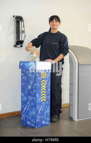 Genève, Suisse - 13 janvier 2014 : jeune fille qui est le recyclage d'une bouteille de PET dans le contenant approprié dans la société cant Banque D'Images