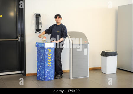 Genève, Suisse - 13 janvier 2014 : jeune fille qui est le recyclage d'une bouteille de PET dans le contenant approprié dans la société cant Banque D'Images