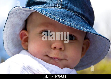 Baby Boy dribbles et portant un chapeau de soleil Banque D'Images