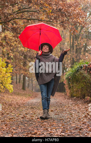 Une femme marche dans la campagne en automne vêtu d'un poncho whool, café de la hat et jeans sur un jour de pluie out Banque D'Images