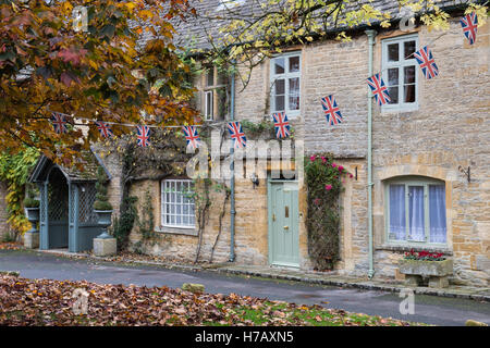 Union jack noir en face de cottages en automne. Stow on the Wold, Gloucestershire, Angleterre Banque D'Images