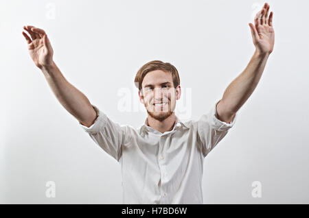 Sourire joyeux, très heureux jeune homme en chemise blanche, bras levés Banque D'Images