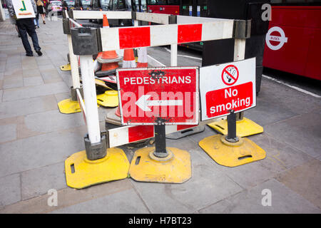 Travaux sur un trottoir à Londres, au Royaume-Uni avec des barrières et des panneaux Banque D'Images