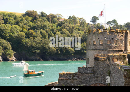 Petite embarcation à moteur chugs dehors à la mer sur la rivière dart passant dartmouth castle au premier plan battant pavillon du patrimoine anglais. Banque D'Images