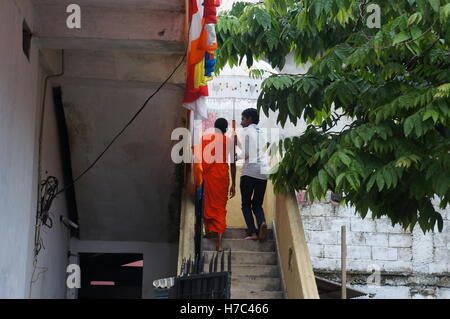 Un jeune homme se tenant un parapluie pour un jeune moine dans un temple bouddhiste prémices à Kandy, Sri Lanka. Banque D'Images