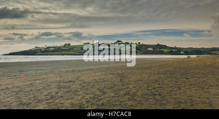 Une vue sur un affleurement de terre dans la mer vue de la plage avec deux minuscules silhouettes pour l'échelle. L'Irlande, 2016 Banque D'Images