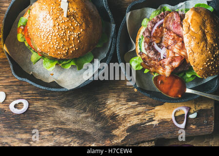 Close-up de hamburgers faits maison avec bacon croustillant et légumes dans de petites casseroles sur fond de bois rustique, vue du dessus, copiez spa Banque D'Images