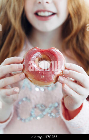 Les beignes glacés rose dans un peu pour les mains. Banque D'Images