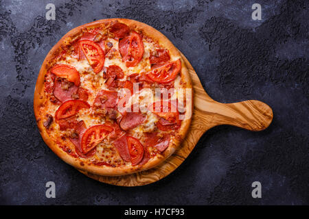 Pizza au jambon et à la tomate olive bois découper sur fond sombre Banque D'Images