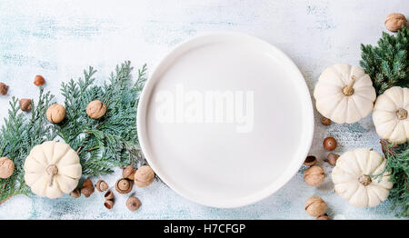 Maison de vacances avec décoration de table blanc citrouilles, thuja branches, de noix, de glands et de vider votre assiette over white woode Banque D'Images